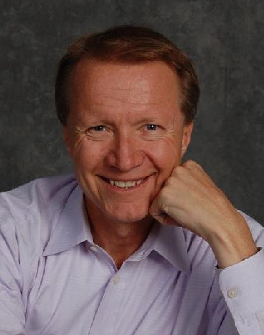 A man in a purple shirt smiling, radiating joy and contentment.